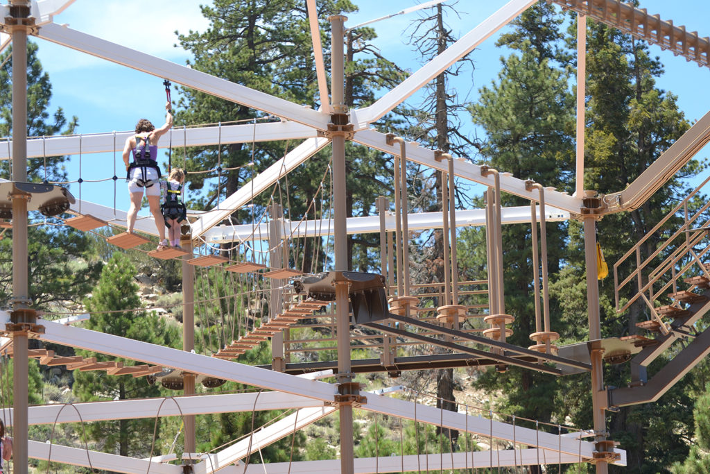 Woman working with young boy to getting through Big Bear Ropes Challenge Course. 